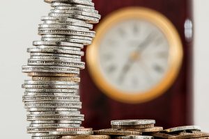 3 Reasons to Hire a Professional Cleaning Company blog - stack of coins in front of blurred clock